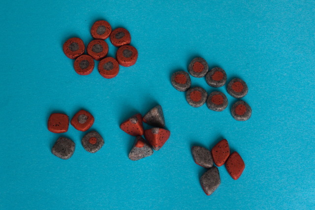 just the game pieces for the royal game of Ur, in red and grey, with 7 + 7 pieces, 4 pyramidal dice, 4 square-ish coins with one side marked with a dot in the other colour and 4 lozenges with the two sides in two different colours.