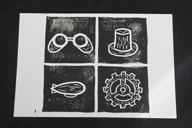 linocut print of four suites in white on black background: goggles, top hat, airship and gear