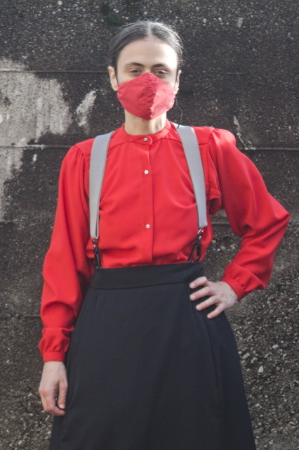The same, standing still, from the front; there is little fullness above the waistline (where it's tucked in the skirt), and it opens with a button placket in the front with 3 visible buttons.