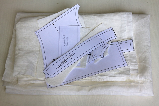 a small pile of cut white fabric, with the paper pattern pieces on top