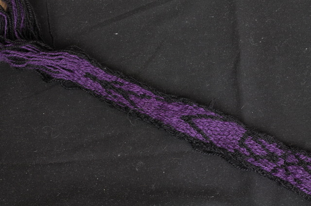 the back of the same band, with a small black border, a purple background in most of the band, and black designs.