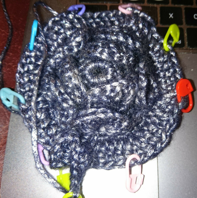 Beginning of a crocheted piece with flaps that look like scales or petals, shimmering beautifully