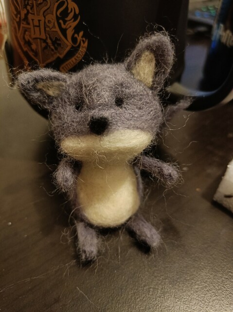 Piccolo lupo grigio con la pancia bianca creato con la tecnica dei needle felting