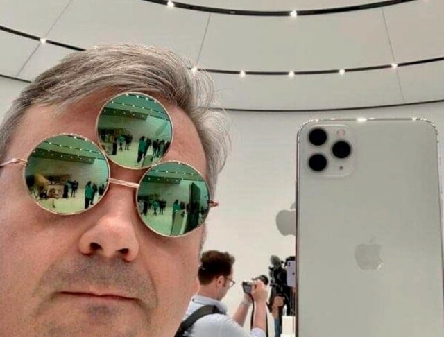 Man wearing triple lens sunglasses while holding up a triple camera smartphone 