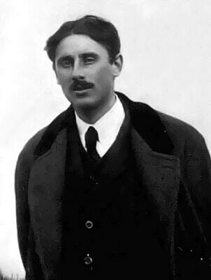 Ritratto di Giovanni Boine. Un giovane uomo, bruno, con un folto paio di baffi, guarda il fotografo. Indossa camicia bianca, cravatta, panciotto e cappotto scuri