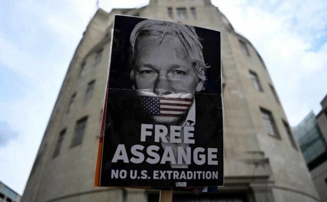 Cartello per la liberazione di Assange fotografato in modo da sembrare una gigantografia affissa sulla facciata di un palazzo