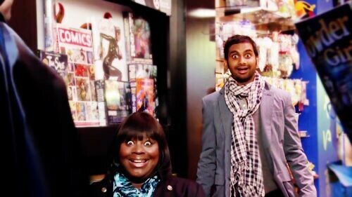Screenshot of the TV show Parks & Recreation, showing the faces of delight on characters Donna and Tom as their colleague Ben comes out of a dressing room in a Batman costume.