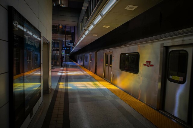 Colour photograph of a subway train on the platform at the Highway 407 station on the Toronto TTC. Coloured light is coming through the glass and lighting the platform