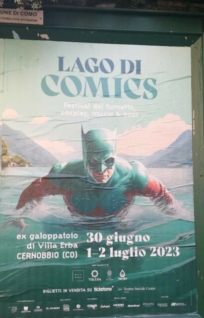 Cartellone pubblicitario di Lago di Comics, ex galoppatoio di Villa Erba, dal 30 giugno al 2 luglio.
Nell'immagine un supereroe mascherato, con un costume rosso e turchese, emerge dalle acque del lago.