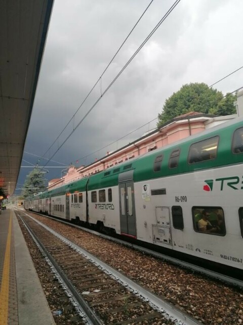 Treno fermo in stazione, con pesanti nuvoloni grigi che si addensano all'orizzonte.