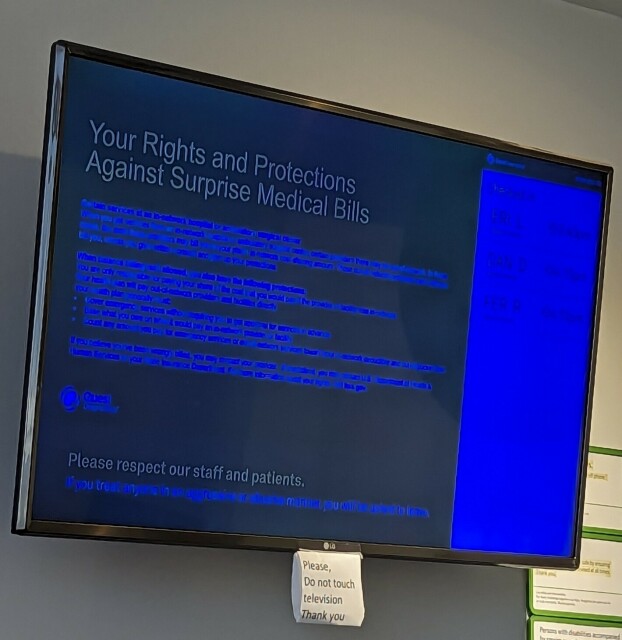 A largely illegible blue-on-black information display on a wall-mounted monitor.