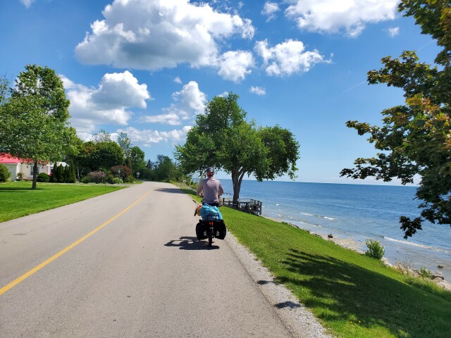 My husband biking along a road next to blue Lake Erie on a sunny day