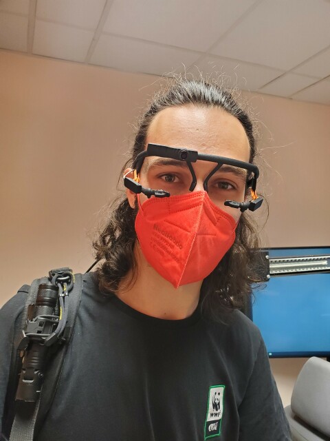Photo de moi, avec un FFP2 rouge et des montures de lunettes avec une micro caméra sous chaque oeil et une sur le front