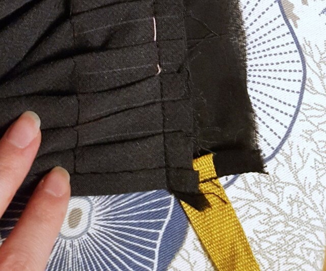 A poor quality close up photo of the same waistband on the inside. The yellow linen tape has been attached to the waistband fabric only, which when folded and sewn down is invisible from the front.