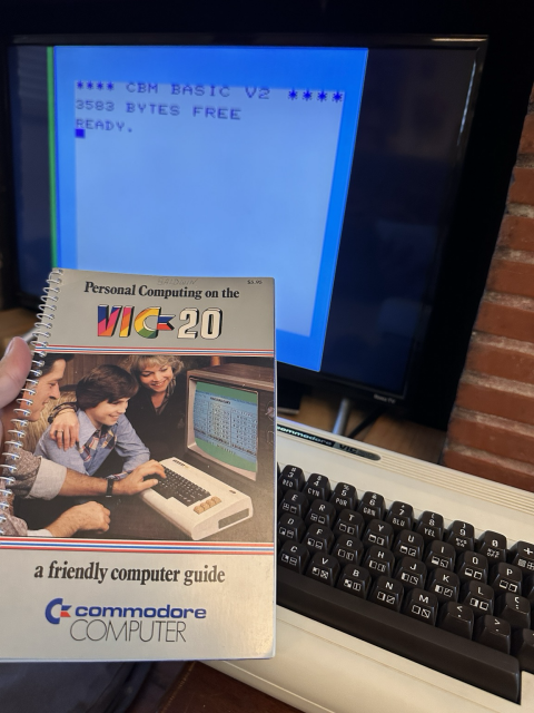A Vic 20 manual and the boot screen of the computer in the background 