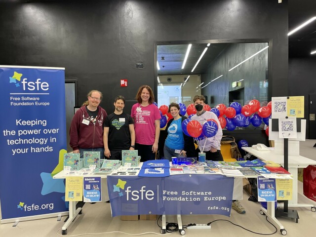FSFE staff members and volunteers behind the FSFE booth at SFSCon
