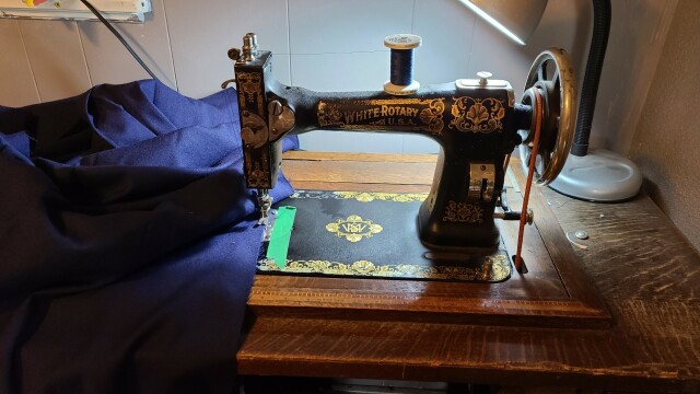 A treadle sewing machine with navy fabric under the foot.