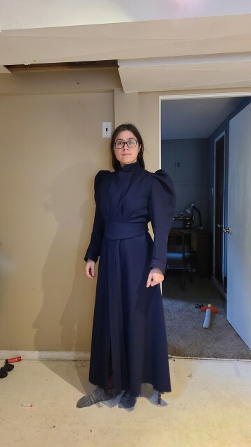 A woman wearing a navy blue dressing gown in the style of 1898.