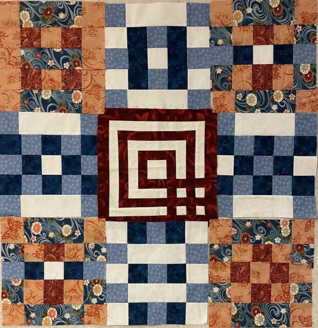 Patchwork quilt made of blues, oranges, red, and white. The center square has a maze like feel. The others alternate the balance of orange and blue and are made from 16 squares. 