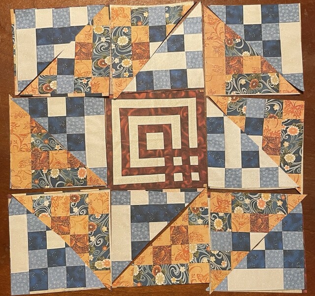 9 patch made of one central block with red/white in a sort of labyrinth. The remaining blocks are blue/white patches for a triangular half and the other triangles are blue and orange. You can see a friendship star formed outside the labyrinth with the blue/white triangles on the inside of the 9 patch.