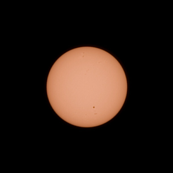 Image of the sun - but taken from Mars! The sun is a pale yellow color and has a few small dark spots on it's surface. The largest one is towards the bottom of the disk next to two smaller ones below. 