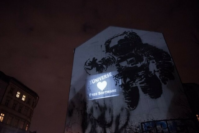 "The universe loves Free Software" text next to an astronaut on a house wall.