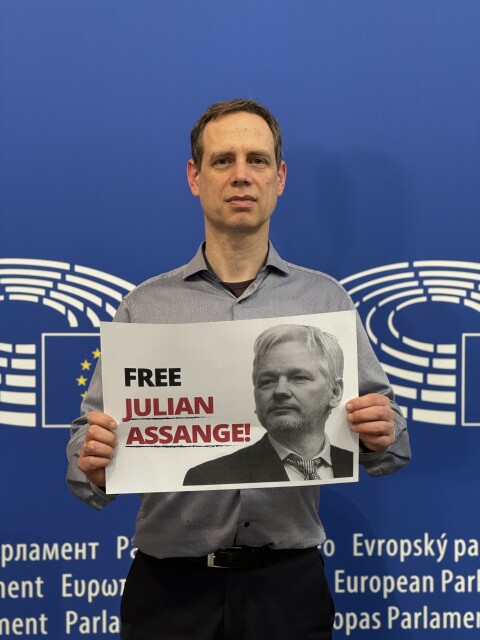 Der Europaabgeordnete Patrick Breyer (Piratenpartei) hält ein Schild "Free Julian Assange"