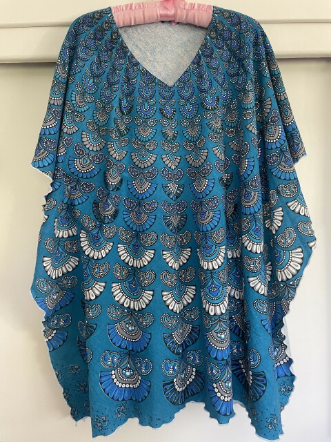 View of kaftan on hanger showing its bias drape and rippled hems. 