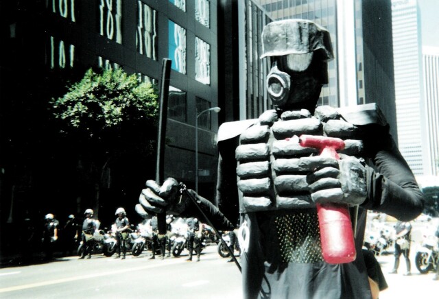 Giant riot cop puppet looking menacing with a foam night stick and super soaker pepper spray held as high in the air as the line of real riot cops strung across the street behind him. 

This photo on a march in downtown Los Angeles at the Democratic national convention in 2000. 