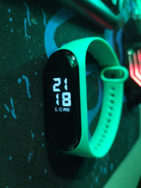 Mi Band 3, sulla mia scrivania, che mosta l'orario corrente con il nuovo tema che ho installato, stile cifre LCD