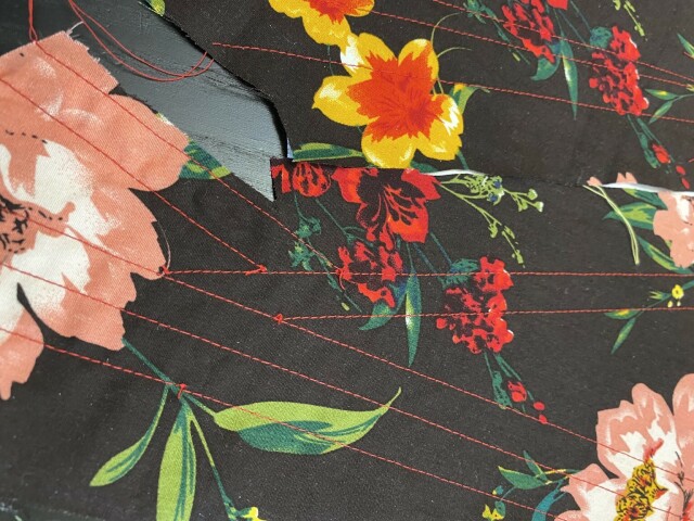 A close up of the red stitching on brown floral fabric