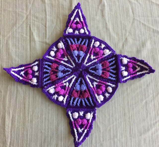 Crochet triangles from the previous post stitched together into an octagon with points sticking out from 4 sides