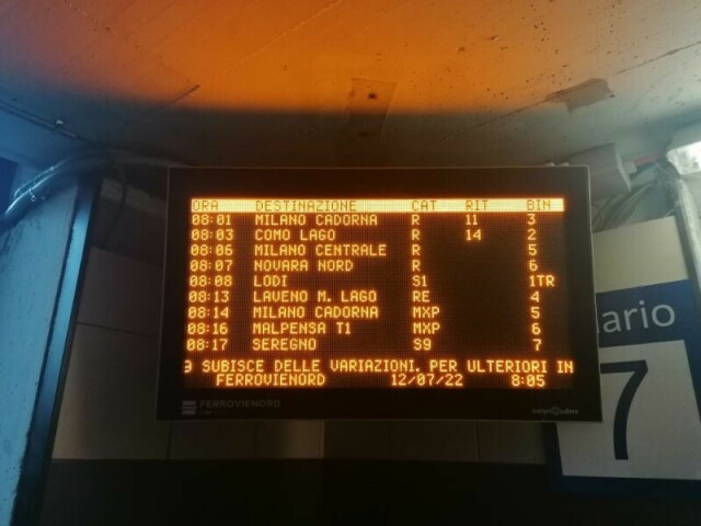 Il tabellone degli orari in stazione: treno per Milano Cadorna in ritardo di 11 minuti, quello per Como Lago in ritardo di 14.