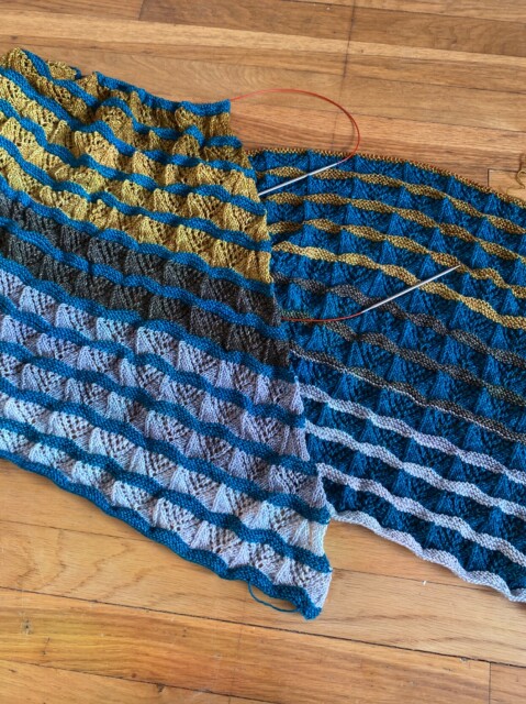 Two knit shawls in progress lying next to one another