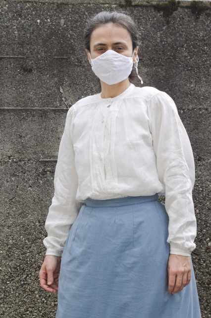 a woman with a white shirt with a short yoke, a button placket and pleats.