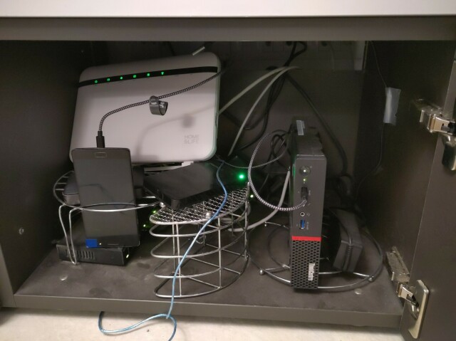 "A cabinet crowded of network gear, a little computer and a smartphone"